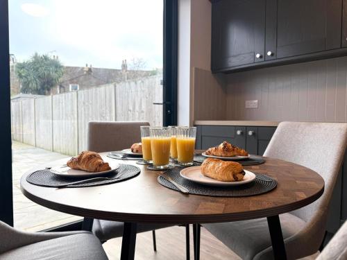 a table with plates of food and glasses of orange juice at Buxton Road Suites in London
