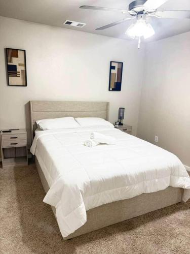 a bedroom with a large white bed with a ceiling fan at The West House Cozy-Modern-Spacious in Midland