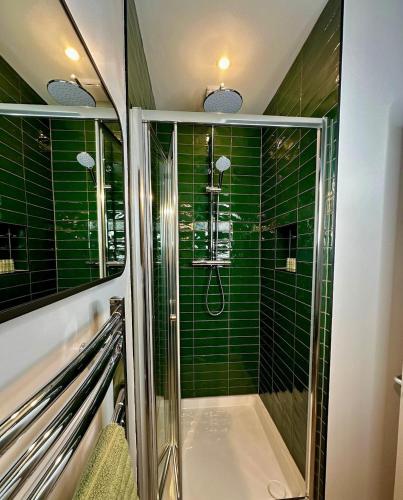 a bathroom with a shower with green tiles at Buxton Road Suites in London