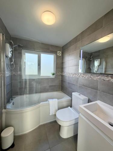 a bathroom with a tub and a toilet and a sink at Spacious Modern 4BR Nottingham City- QMC- Uni in Nottingham