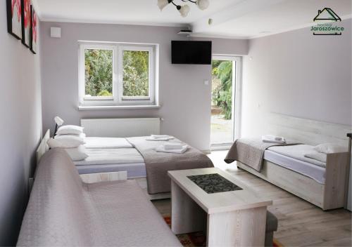 a white room with two beds and a table at Noclegi Jaroszowice in Jaroszowice