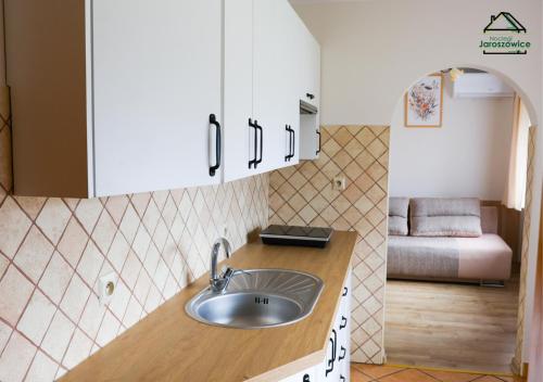 a kitchen with a sink and a room with a bed at Noclegi Jaroszowice in Jaroszowice