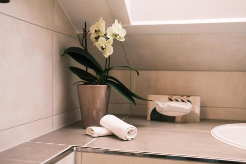 a bathroom with a vase with a plant and towels at Restaurant & Landhotel Winter in Gomadingen