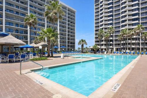 a large swimming pool with palm trees and buildings at Saida Towers III- 3101 condo in South Padre Island