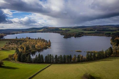 an aerial view of a lake with trees in the middle at Lodge at Lochside in Bridgend of Lintrathen