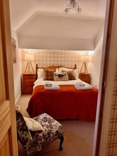 a bedroom with a bed with red sheets and a chair at Lodge at Lochside in Bridgend of Lintrathen