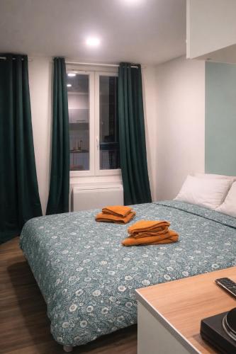 two orange towels sitting on a bed in a room at Petit cocon moderne Cuisine équipée TV WIFI in Roubaix