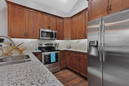 a kitchen with wooden cabinets and stainless steel appliances at Comal Cottage in Canyon Lake