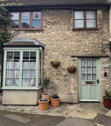 a stone building with a green door and potted plants at Lilywood Cottage - 2BR Central Bicester in Bicester
