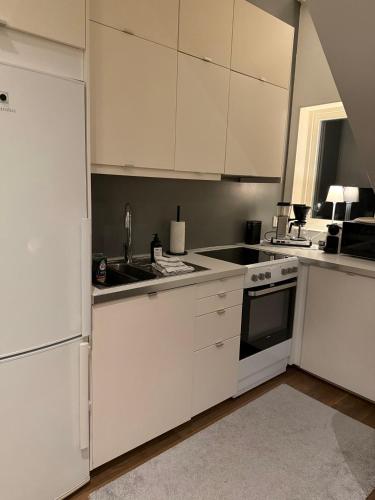 a kitchen with white cabinets and a sink at Cozy apartment in Kungsbacka
