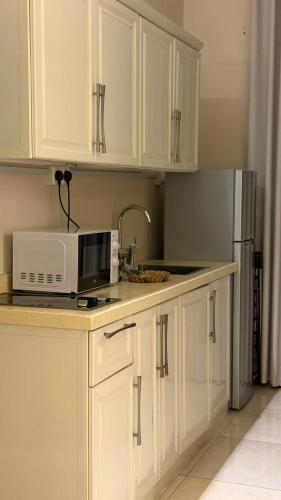 a kitchen with white cabinets and a microwave and a refrigerator at نوليتا للشقق الفندقية in Abha