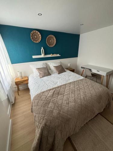 a bedroom with a large bed and a blue wall at La Parenthèse in Chalons en Champagne