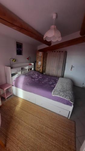 a bedroom with a bed with a purple comforter at Chambre "Là Maison Haute" in Faucon