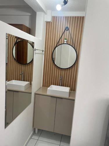 a bathroom with two sinks and two mirrors at Apartamento com piscina in Ponta Grossa
