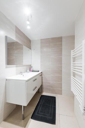 a white bathroom with a sink and a mirror at Les Remparts du Loing in Moret-sur-Loing