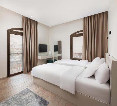 a white bedroom with a large bed and a television at Sleep Inn Apart-Hotel in Cairo