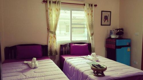 two beds sitting next to each other in a bedroom at Lampang Lanna Home in Lampang