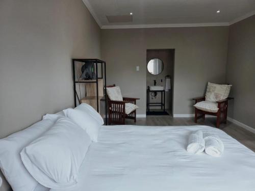 a bedroom with a white bed and two chairs at Munnik Rest in Polokwane