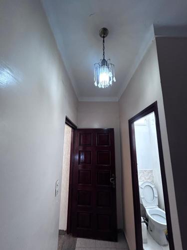 a bathroom with a door and a toilet and a chandelier at Tabriquet urban shared room in Salé