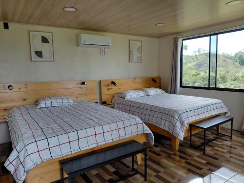 two beds in a room with a window at Villa Lago del Sol in El Castillo de La Fortuna