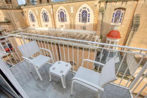 a balcony with two chairs and a table and a building at The Bellview Suite - Luxury 1 BR APT - Central Gzira in Il-Gżira