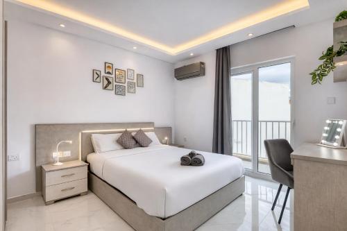 a white bedroom with a bed and a balcony at The Bellview Suite - Luxury 1 BR APT - Central Gzira in Il-Gżira