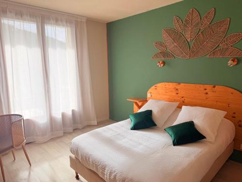 a bedroom with a large bed with green walls at Hôtel Des Rochers in Marvejols