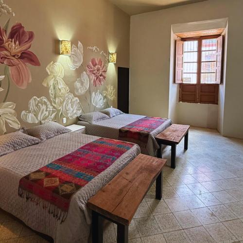 two beds in a room with flowers on the wall at La Casa de Ticho in Mascota