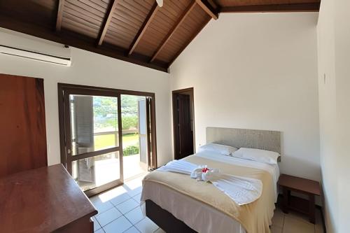 a bedroom with a bed and a large window at Casa Morrinhos 01 in Garopaba