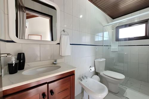 a bathroom with a sink and a toilet and a mirror at Casa Morrinhos 01 in Garopaba