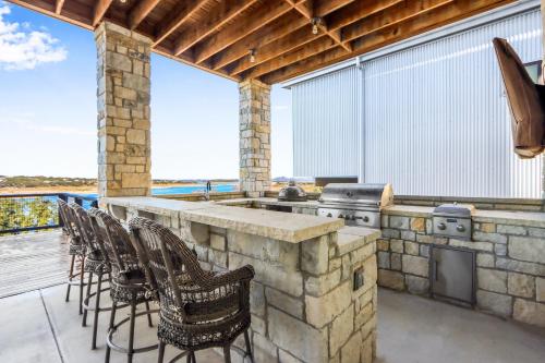 an outdoor kitchen with chairs and a grill on a deck at Lakeside Dreamhouse in Canyon Lake