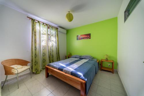 a bedroom with green walls and a bed and a chair at KazAKaty in Trois-Rivières
