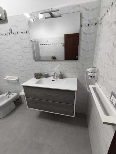 a white bathroom with a sink and a mirror at Casa Sciacca: La Tua Casa Vacanze Ideale a Marsala in Marsala