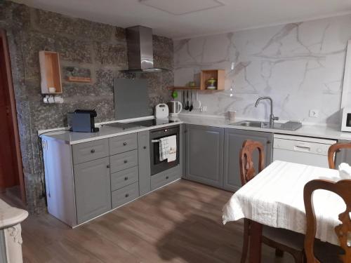 a kitchen with white counters and a sink and a table at Casa do Pátio - Férias no Douro in Baião