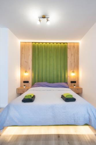 a bedroom with a large bed with a green headboard at NXN Airportstay in Cluj-Napoca