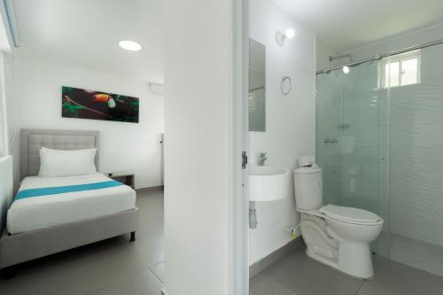 a white bathroom with a toilet and a shower at Hotel Villa Mónaco in Pereira