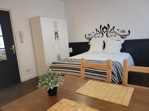 una camera da letto con un letto con testiera nera e una sedia di Studio 1 du Temple Hyper Centre a Cambrai