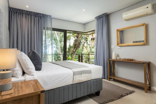 a bedroom with a bed and a large window at 23 The Sanctuary Zimbali in Ballito