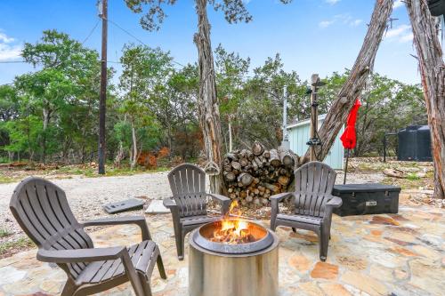 three chairs and a fire pit with a pile of logs at Lakeview A-Frame in Canyon Lake