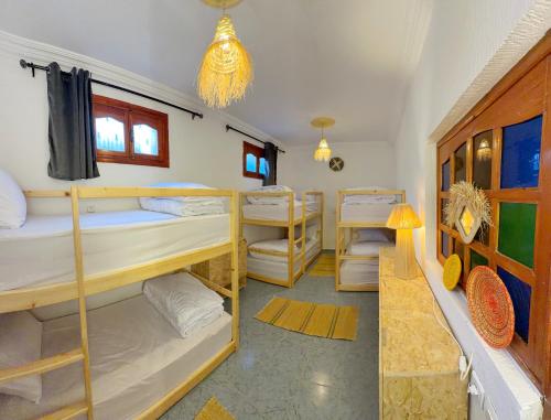a room with several bunk beds in a room at Blue Tizirin House in Tamraght Ouzdar