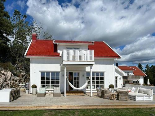 a white house with a red roof and a patio at Modern & Charming Summer House Near Risør in Søndeled