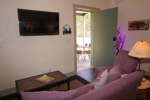a living room with a purple couch and a flat screen tv at Lavender in Wimberley