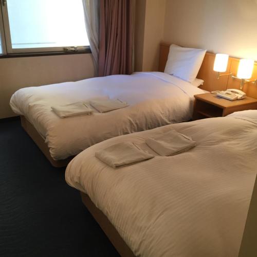 a hotel room with two beds and a window at Hotel Crown Hills Kofu in Kofu