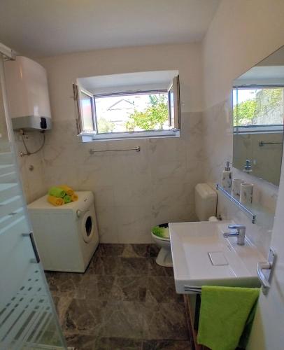 a bathroom with a toilet and a sink and a window at House Veli Iz oldtown in Veli Iž
