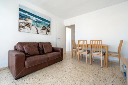 a living room with a couch and a table and chairs at Hauzify I Apartament Esmeralda in L'Ametlla de Mar