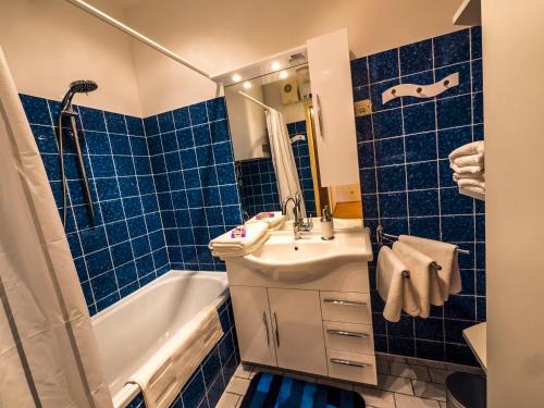 a blue tiled bathroom with a sink and a tub at Apartment "Maria Theresia" in Graz