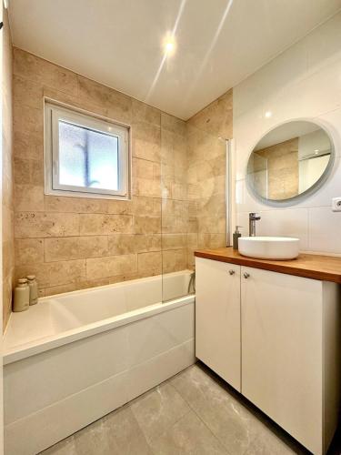 a bathroom with a tub and a sink and a bath tubermottermott at Studio Cosy in Mimizan-Plage