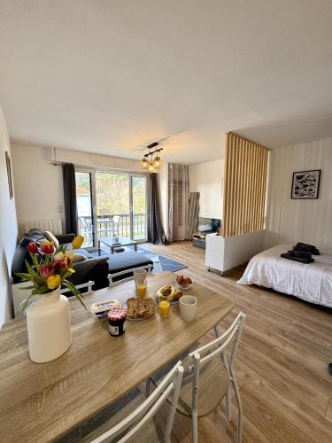 a living room with a table and a room with a bed at Studio Cosy in Mimizan-Plage
