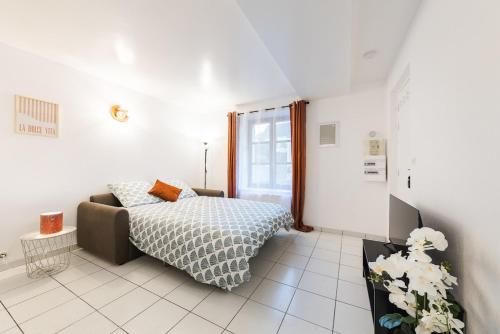 a white bedroom with a bed and a window at Le Carnot Garden in Étampes