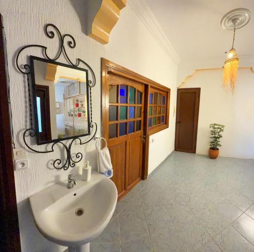 a bathroom with a sink and a mirror on the wall at Blue Tizirin House in Tamraght Ouzdar
